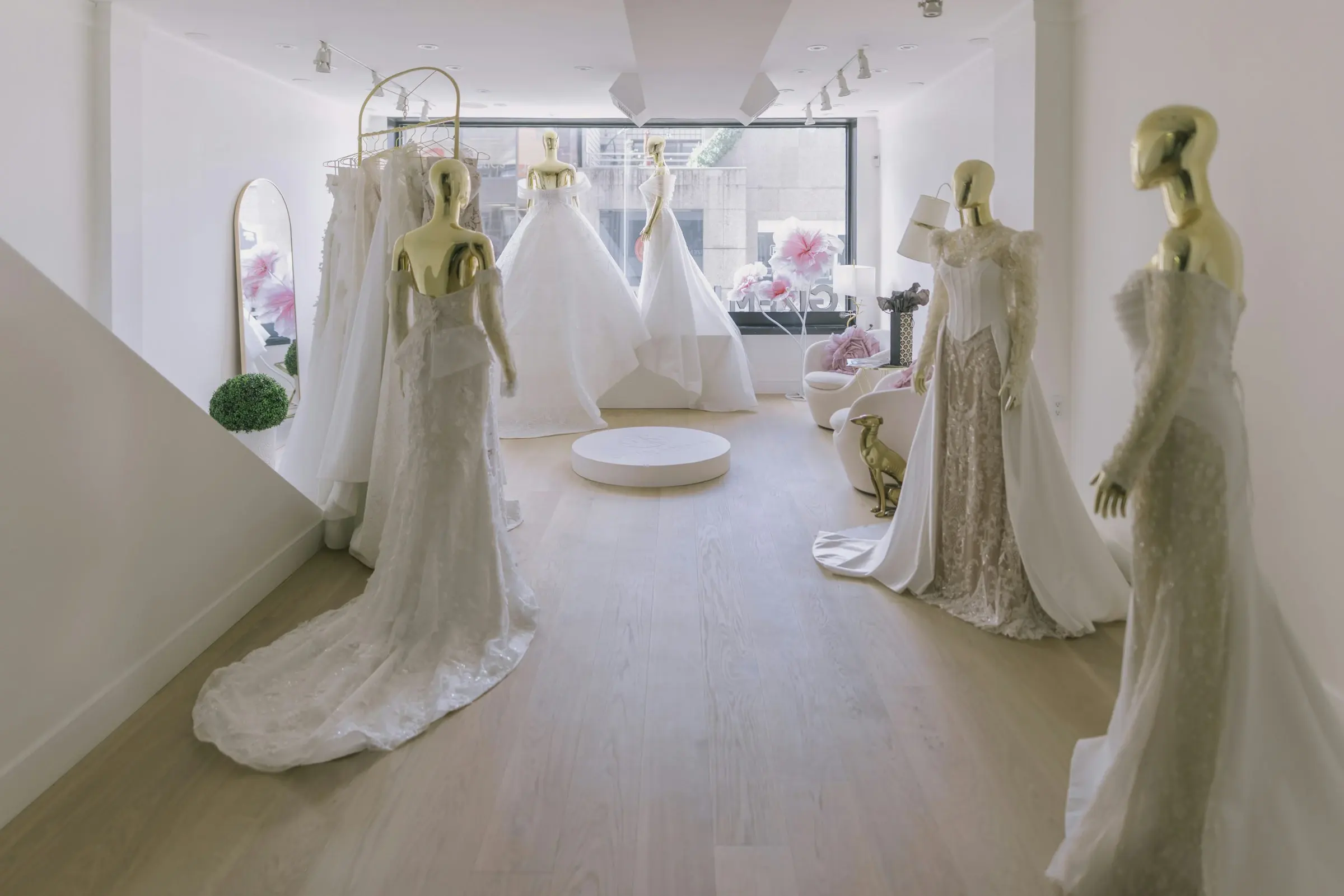 Wedding gowns displayed on mannequins in a bright bridal boutique